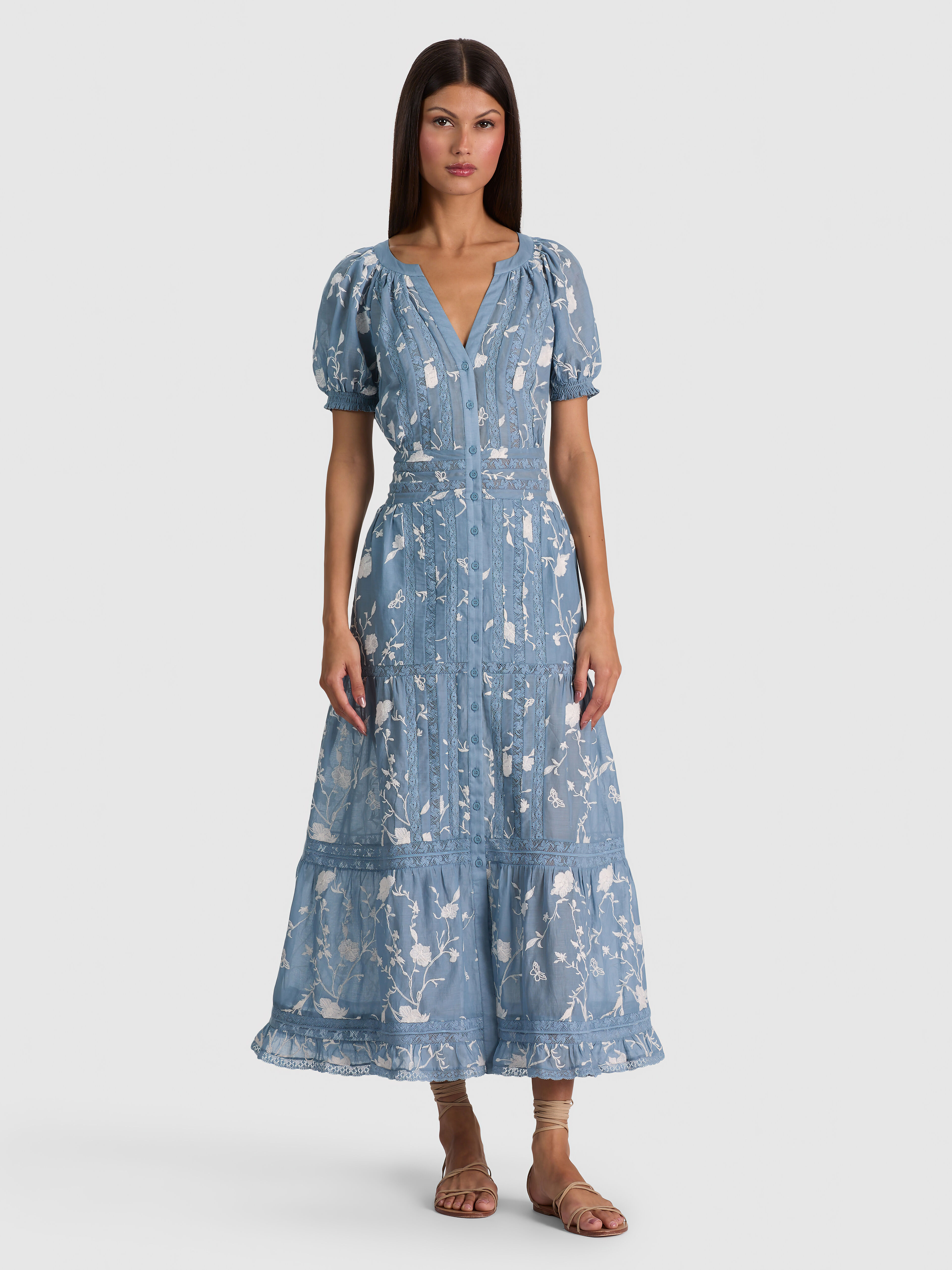 A model wearing the ALICE + OLIVIA Kathryn Midi Shirt Dress in cotton voile with puffed short sleeves and embroidered lace, styled casually with loafers.