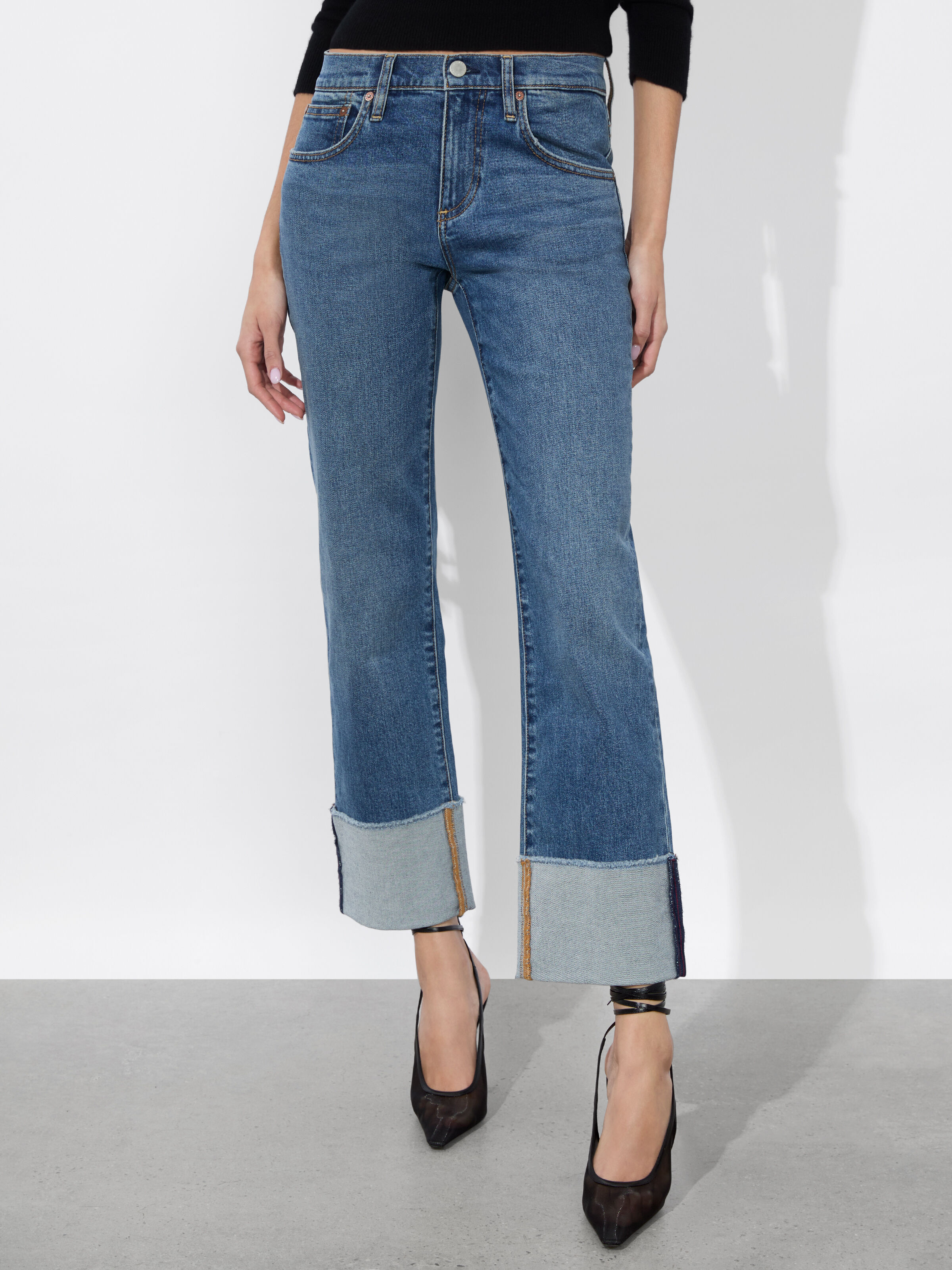 A full-length shot of a woman wearing the ALICE + OLIVIA Abilene Cuffed Jean with raw hem cuffs and a skinny leg silhouette, representing the cuffed and structured denim trend for 2026.