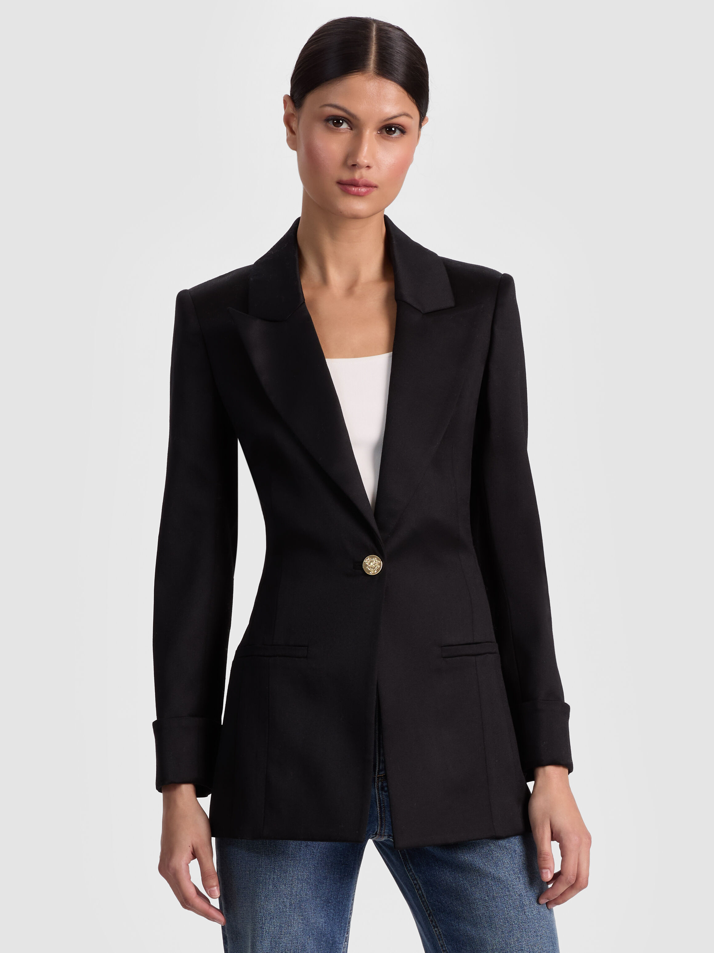 A model wearing the ALICE + OLIVIA Burns Fitted Blazer styled as a classic tailored suit with matching trousers, shot in a polished editorial setting.
