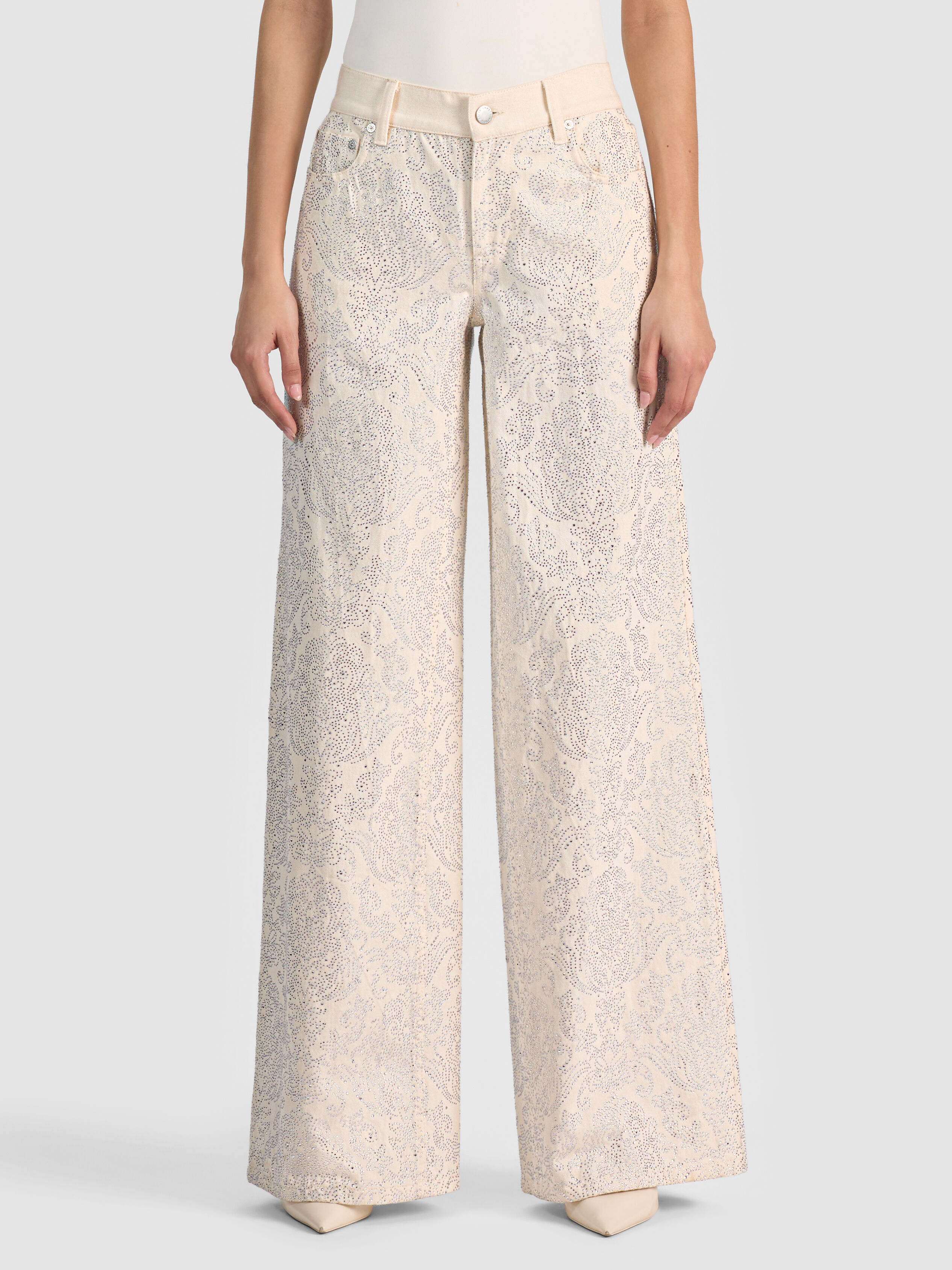 A woman wearing the ALICE + OLIVIA Amazing Embellished Jean with a crystal-embellished paisley print, illustrating the printed and statement denim trend for 2026.