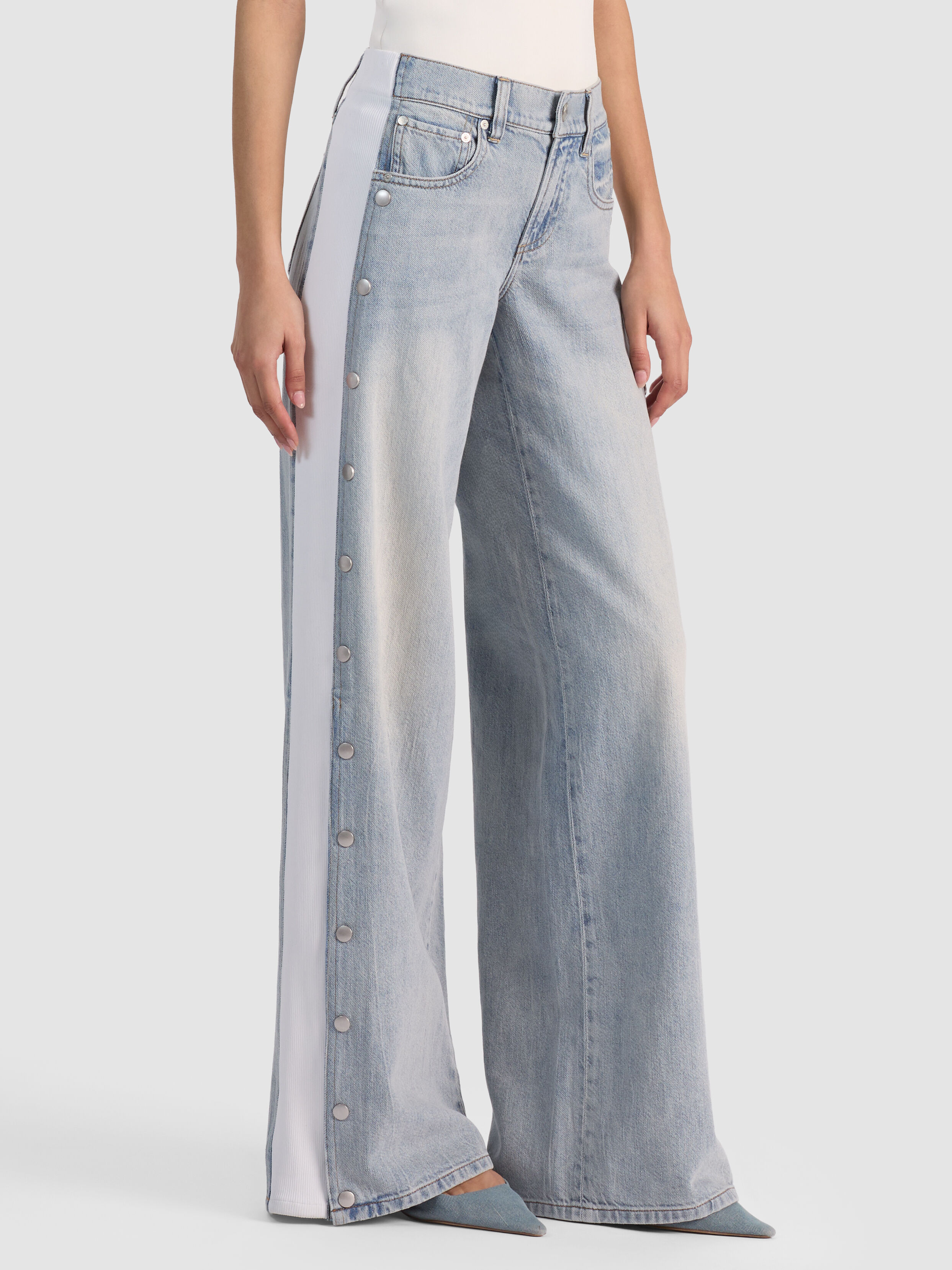 A full-length shot of the ALICE + OLIVIA Amazing Snap Jean showing the mixed media side panels with snap closures at the hem, representing the split-hem and modern denim details trend for 2026.