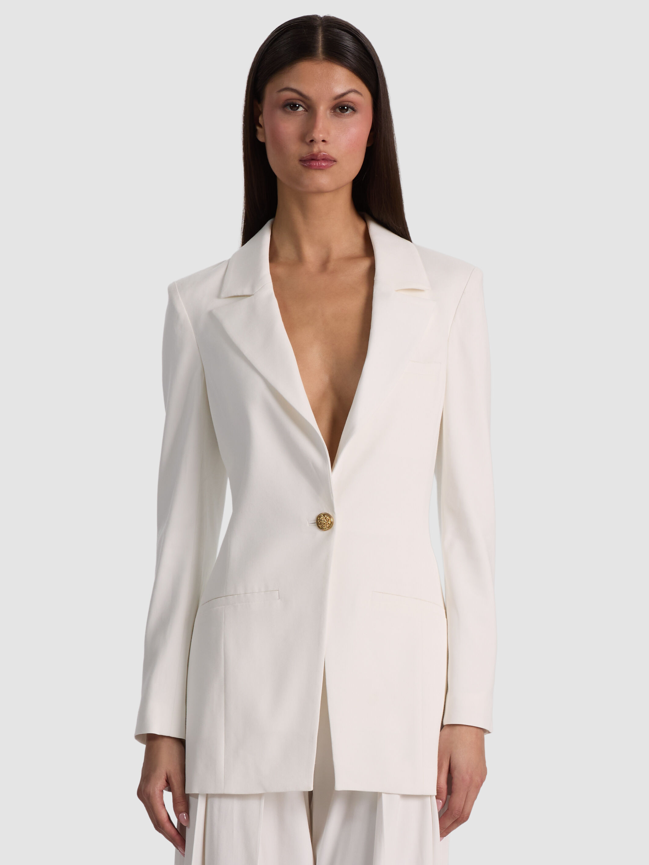A woman styled in a dressy casual women's outfit featuring the ALICE + OLIVIA Hope Fitted Blazer in lightweight twill, paired with tailored trousers and refined flats — polished, modern, and effortlessly chic.